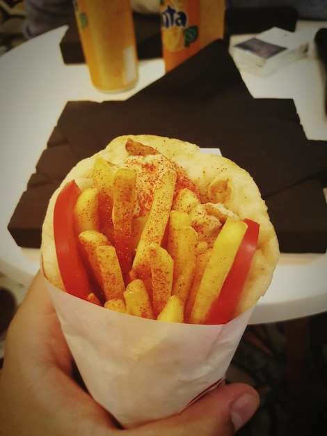 Foto primer plano de una mano recortada sosteniendo patatas fritas