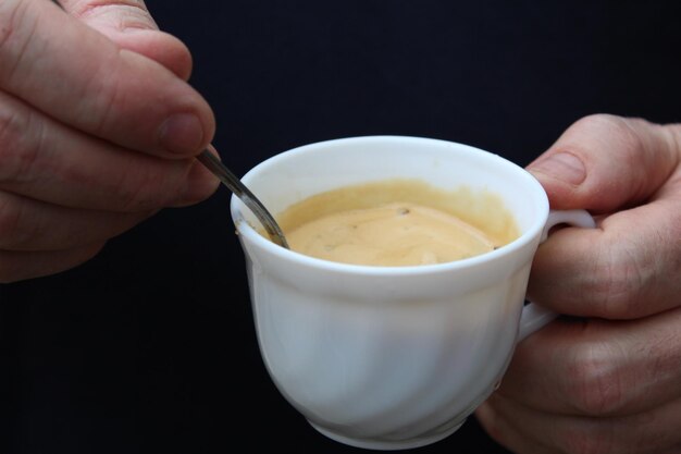 Primer plano de una mano recortada sosteniendo una taza de café