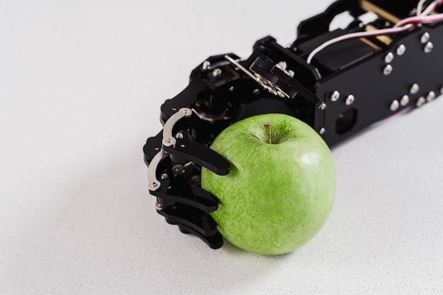 Primer plano de la mano de un robot real con manzana verde Concepto de desarrollo de inteligencia artificial y automatización de procesos robóticos