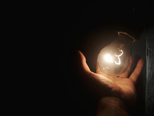 Foto primer plano de una mano sosteniendo una bombilla iluminada