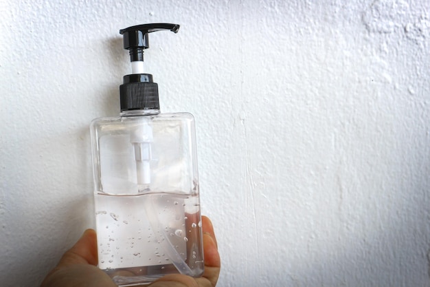 Foto primer plano de la mano sosteniendo la botella contra la pared