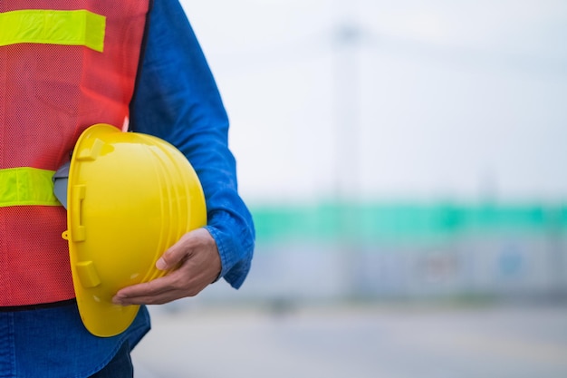 Primer plano mano sosteniendo casco blanco casco Concepto de ingeniería Técnico sosteniendo casco casco de seguridad fondo solar