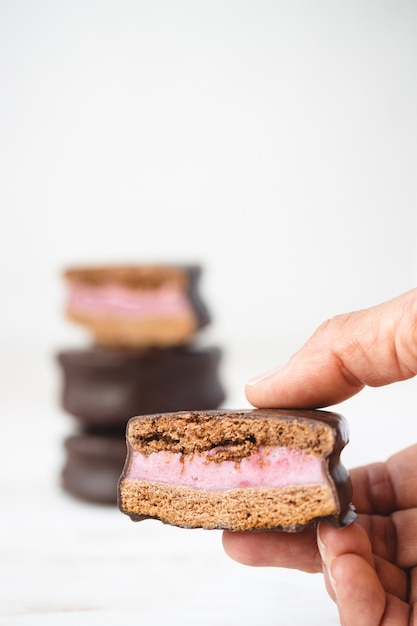 Primer plano de una mano sosteniendo un chocolate cubierto de galletas con relleno. Galletas sandwich.