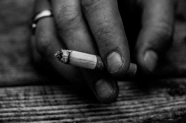 Foto primer plano de la mano sosteniendo un cigarrillo