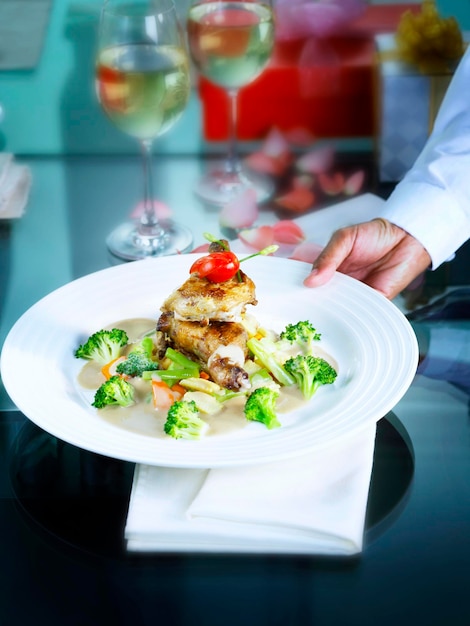 Foto primer plano de la mano sosteniendo la comida en el plato sobre la mesa