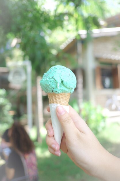 Foto primer plano de una mano sosteniendo un cono de helado en el patio