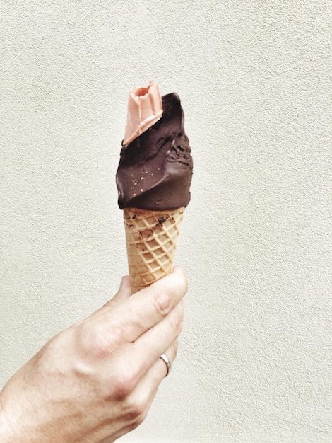 Primer plano de una mano sosteniendo un cono de helado