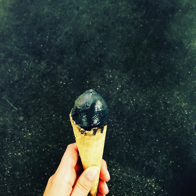 Primer plano de una mano sosteniendo un cono de helado