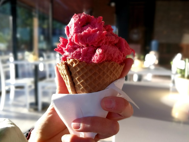 Primer plano de una mano sosteniendo un cono de helado