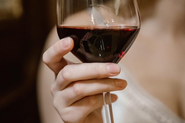 Primer plano de una mano sosteniendo una copa de vino rojo
