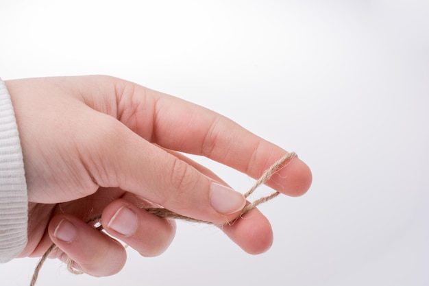 Primer plano de la mano sosteniendo la cuerda contra un fondo blanco
