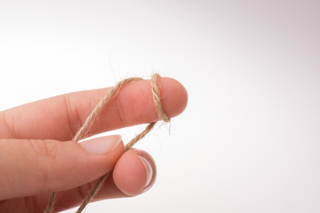 Primer plano de la mano sosteniendo la cuerda sobre un fondo blanco