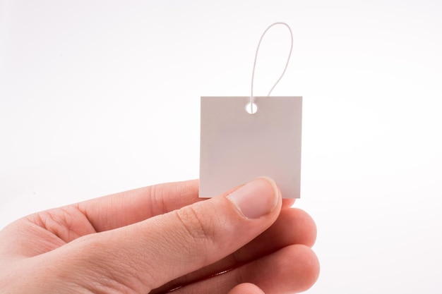 Primer plano de una mano sosteniendo una etiqueta en blanco contra un fondo blanco