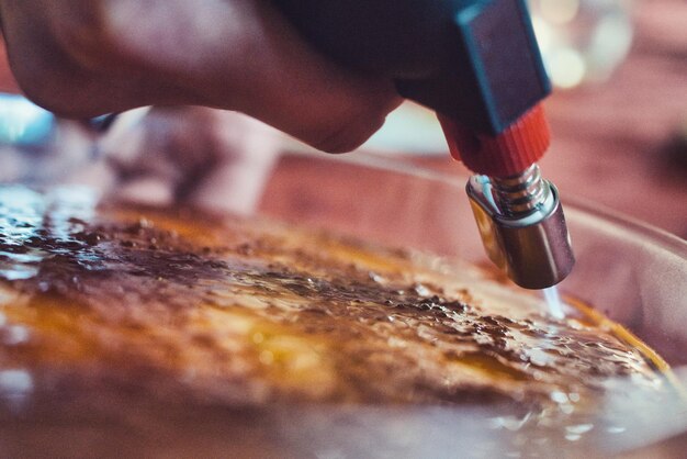 Foto primer plano de la mano sosteniendo la flamba por encima de la crema brulee