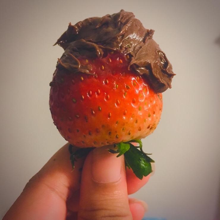 Foto primer plano de una mano sosteniendo una fresa sobre un fondo blanco