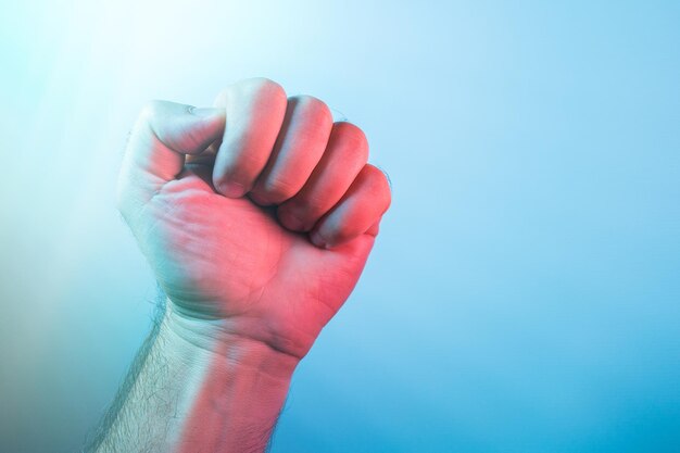 Foto primer plano de la mano sosteniendo una hoja roja contra el cielo azul