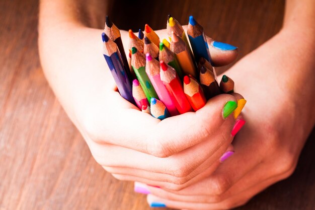 Primer plano de una mano sosteniendo lápices de color