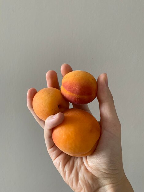 Primer plano de la mano sosteniendo una manzana contra un fondo blanco