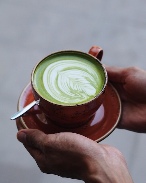 Primer plano de la mano sosteniendo el matcha latte