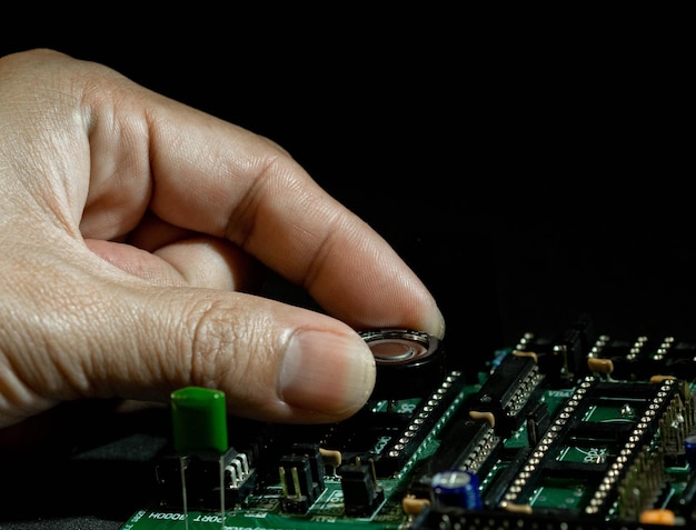 Foto primer plano de una mano sosteniendo parte de la placa del controlador sobre un fondo negro