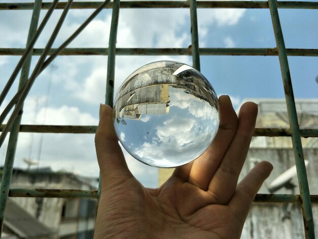 Foto primer plano de la mano sosteniendo la pelota de vidrio contra la ventana