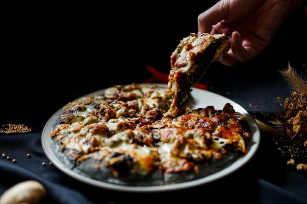 Primer plano de la mano sosteniendo la pizza en el plato