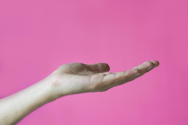 Foto primer plano de la mano sosteniendo un producto invisible contra un fondo rosado