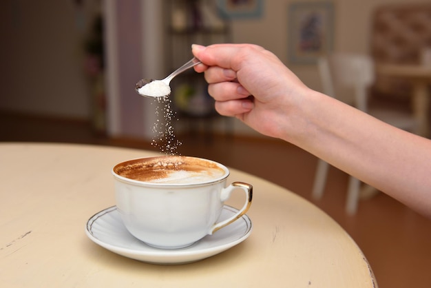 Primer plano de una mano sosteniendo una taza de café en la mesa