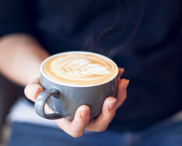 Primer plano de una mano sosteniendo una taza de café