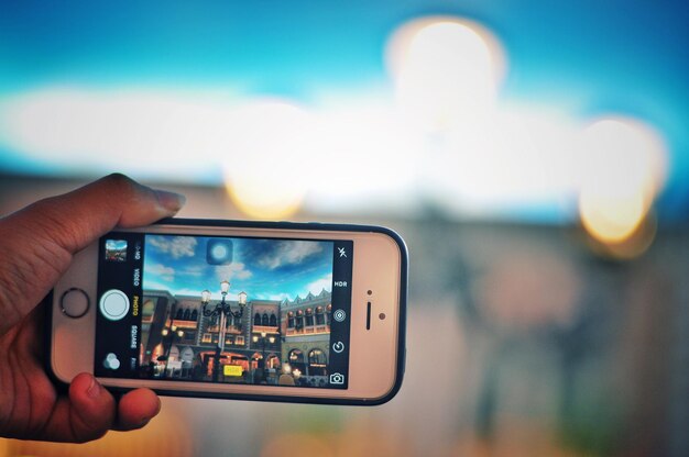 Foto primer plano de la mano sosteniendo el teléfono inteligente contra el cielo