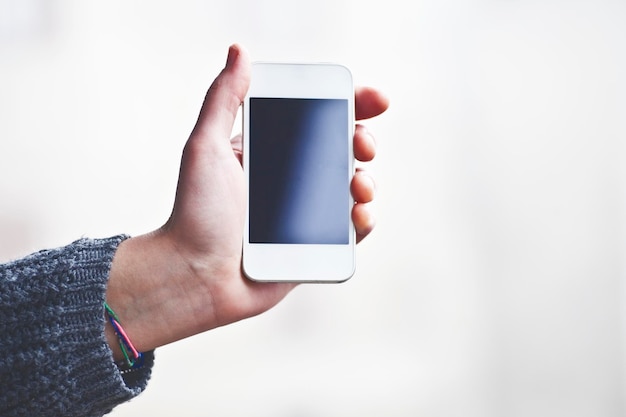 Foto primer plano de la mano sosteniendo el teléfono inteligente contra un fondo blanco