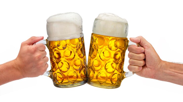 Foto primer plano de una mano sosteniendo un vaso de cerveza contra un fondo blanco