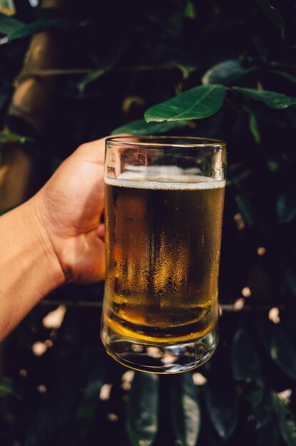 Foto primer plano de una mano sosteniendo un vaso de cerveza