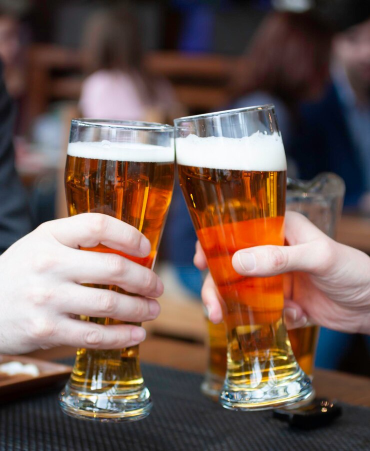 Foto primer plano de una mano sosteniendo un vaso de cerveza