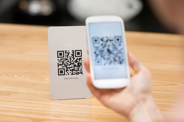 Foto primer plano de una mano sujetando el teléfono y escaneando el código qr