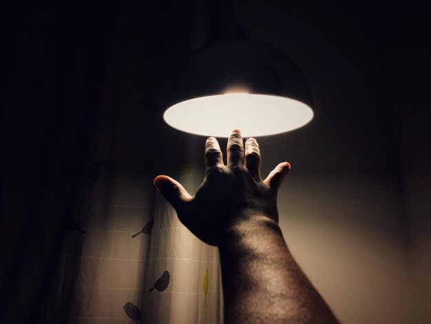 Foto primer plano de la mano tocando una bombilla iluminada