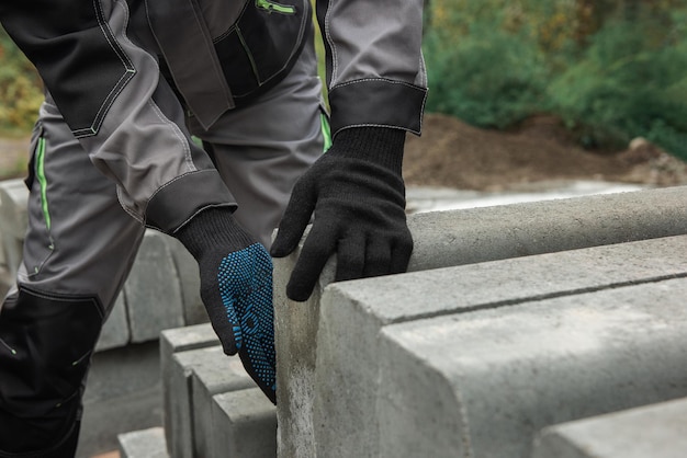 Primer plano de la mano de un trabajador en un guante protector con concepto de construcción de bordillo de carretera