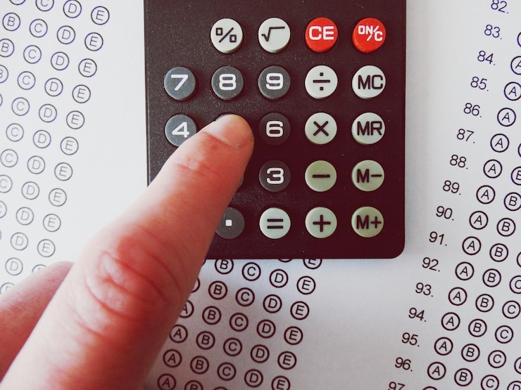 Foto primer plano de la mano usando una calculadora sobre papel