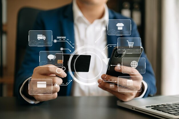 Primer plano de la mano usando una tarjeta de crédito y una computadora portátil con un teléfono inteligente en un escritorio de madera con un diagrama gráfico de iconos de VRxA