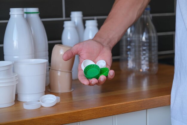 primer plano de la mano con vasos de botellas de plástico de colores en el fondo de muchos residuos plásticos