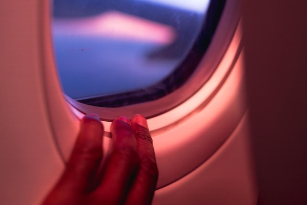 Primer plano de una mano en la ventana de un avión