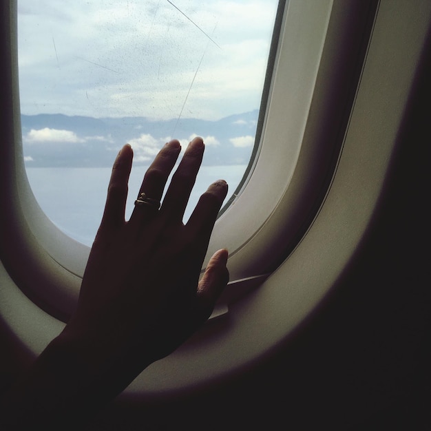 Primer plano de una mano en una ventana mojada de un avión