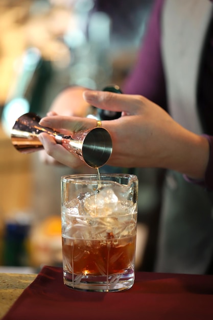 Primer plano de la mano vertiendo la bebida en un vaso sobre la mesa
