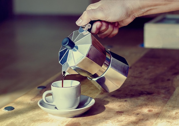 Primer plano de la mano vertiendo café