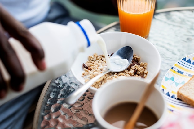 Primer plano de mano vertiendo leche en cereales