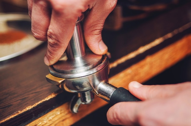 Primer plano de una mano vierte café baristas en el soporte. Enfoque suave