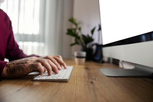 Primer plano de las manos de un anciano de 39 años escribiendo en un teclado en la oficina de casa