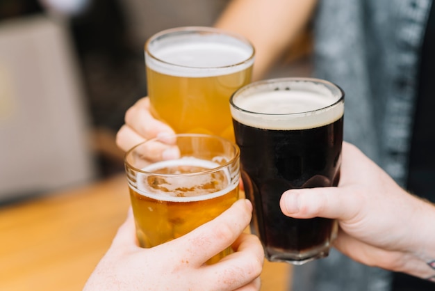 Primer plano de manos animando los vasos de cerveza