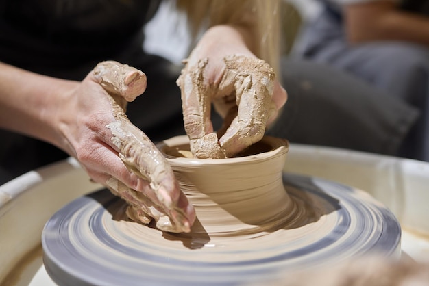 Primer plano de las manos de los artesanos que trabajan con arcilla en el estudio de alfarería