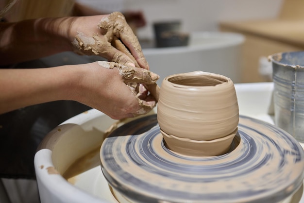 Primer plano de las manos de los artesanos que trabajan con arcilla en el estudio de alfarería